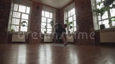 做一个体式的年轻人。 城市工作室黑色垫子上的瑜伽大师练习