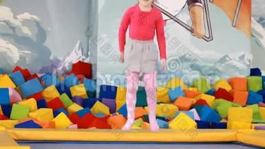 小女孩在蹦床上玩耍和跳跃。 孩子们在操场上玩耍和跳跃