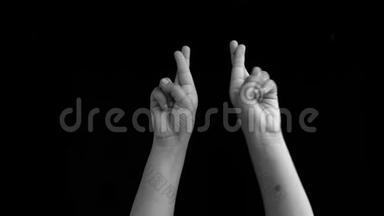 <strong>双手</strong>举起，显示和平手势或好运标志或<strong>交叉</strong>手指孤立在黑色背景。