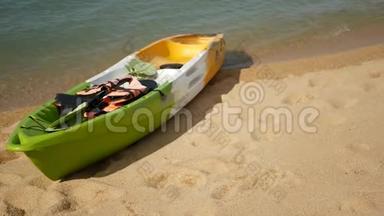 用桨划在沙滩上的皮艇，被蓝色的海水冲刷。 五颜六色的独木舟在波浪状的水晶水中，热带寂寞