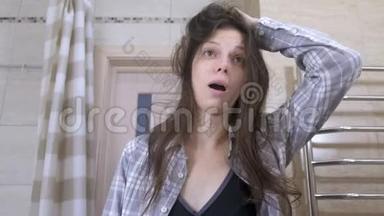 睡醒的戴眼镜的女人用手<strong>梳头</strong>发，在浴室里打哈欠。