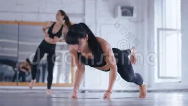 运动型美女在交叉健身馆的地板上做俯卧撑。 女运动员在健身房锻炼。 交叉装备