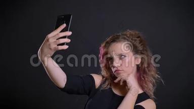 年轻的高加索女孩的肖像，粉红色的头发制作自拍-照片使用智能手机在黑色背景。