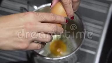 女人的手在碗里砸鸡蛋。 在厨房<strong>打碎</strong>一个鸡蛋。 慢动作。
