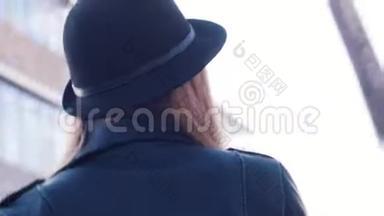 春夏<strong>时节</strong>，一位戴着深色帽子和黑色皮夹克的漂亮年轻女子正在观看摄像机