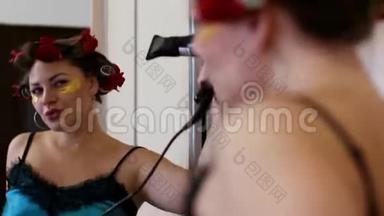 迷人的女人在吹风机里唱歌。一个女人在家里用吹风机唱歌的肖像。美女模特玩得开心