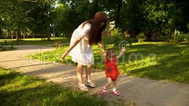 婴儿和她的母亲一起<strong>迈出第一步</strong>，跪倒在她的膝盖上，沿着公园的行走。 慢动作