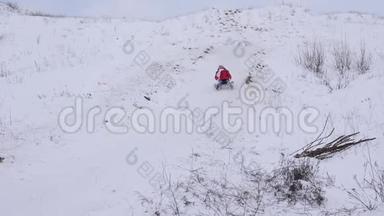 快乐的孩子在雪中滑下山，笑。 雪飞到女孩面前。 公园里的圣诞节假期