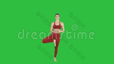 年轻女子练习瑜伽，站在Utthita Hasta Padangustasana锻炼，伸出手向大脚趾摆出绿色的姿势