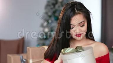 充满好奇心的年轻亚洲女人打开<strong>圣诞</strong>礼物盒，微笑的中等特写肖像