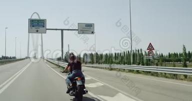 年轻夫妇骑摩托车在高速公路上，从后面拍摄视频，阳光明媚的一天。