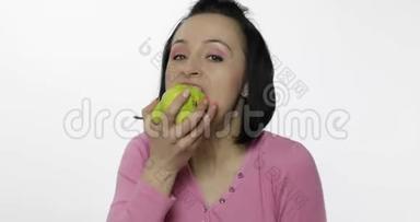 年轻漂亮的女人在白色背景上吃着大而多汁的绿梨