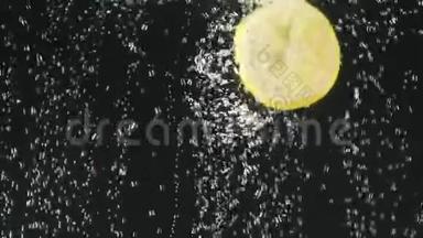 新鲜柠檬片落入水中的黑色背景。 柠檬在水中有气泡。 有机食品。 慢动作。