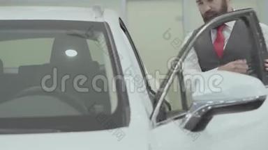 画像上有魅力、自信、长胡子的商人坐在车里，检查从车里买的新车