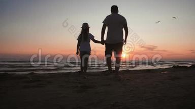 剪影父女在日落时在海滩上玩耍。 友好家庭，旅游，生活方式的概念..