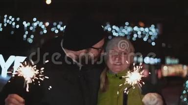 幸福的一对，夫妻相约新年又亲.. 冬天在外面。 他们手里拿着火花，反对