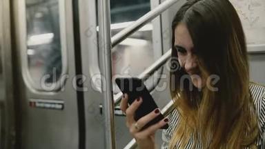 快乐迷人的千禧自由职业者女孩坐在地铁列车上使用社交网络智能手机应用程序和微笑。