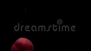 三个成熟的桃子在黑色的背景下落入透明的水中