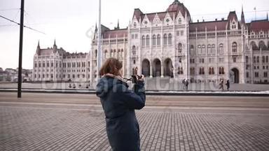 旅游妇女在布达佩斯的议会附近拍摄秋季或冬季的照片