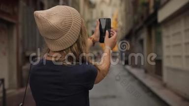 一位年轻时尚、美丽的年轻千禧一代女士在一个欧洲老城区的街道上拍摄<strong>智能</strong>手机<strong>摄像头</strong>