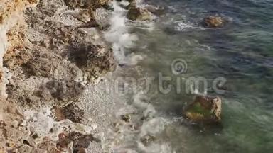 海浪在海滩上的湿岩石上溅起浪花。