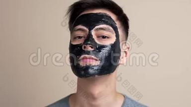 戴着黑色化妆面具的漂亮年轻人用慢镜头、视频肖像、面部护理、自拍视频看镜头