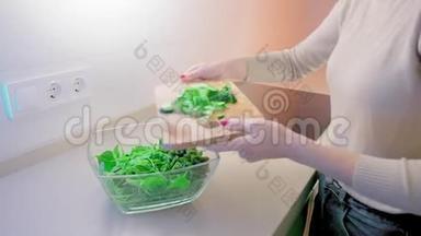 动作缓慢，一个未被认出的女人把切好的黄瓜倒在木板上，放进一个玻璃沙拉碗里，里面有一个<strong>大厨</strong>房