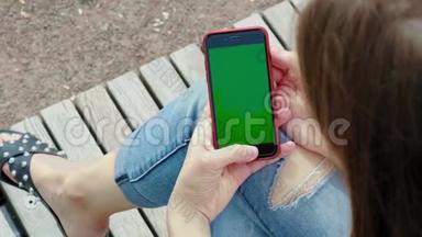 美丽的女孩手里拿着黑色的智能手机，手里拿着绿色的屏幕，手里拿着手机智能手机。