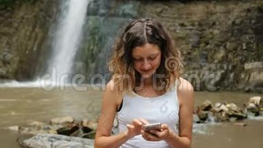 女人在大自然中使用智能手机，背景是一个大瀑布，依赖互联网
