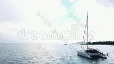 空中观赏一艘停泊的双体帆船，人们可以在甲板上`日光浴。