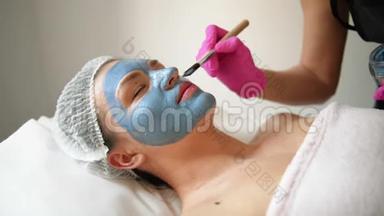 去脸面膜，水疗美容治疗，护肤.. 女人在水疗沙龙接受美容师的面部护理。 女人做女人