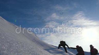 登山者双手互相帮助爬上一座下雪的小山。 冬季旅游中协调良好的团队合作。 小组成员