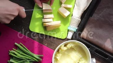 女人在切割板上切奶酪。 旁边的其他<strong>食材</strong>做菜饭.. <strong>土豆</strong>泥，新鲜洋葱羽毛。