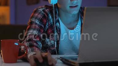 沉迷耳机的男青少年晚上玩网络游戏，紧张的行为