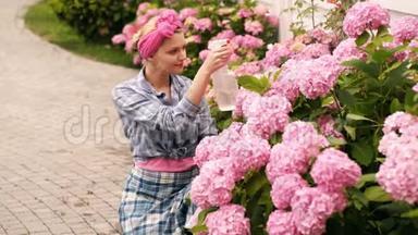 快乐的女孩在<strong>浇花</strong>。 女人<strong>浇花</strong>。 女人关心鲜花。 女人在花园里浇了粉红色的绣球花