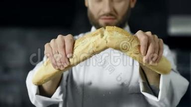 厨师慢动作打破法式面包。 特写面包师手破面包。