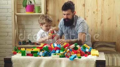 家庭和童年的概念.. 爸爸和孩子搭建塑料积木.. 有着快乐面孔的父子创造了丰富多彩的玩具