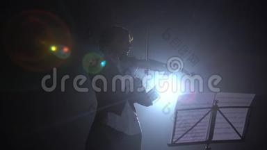 小提琴手拿着灯笼在舞台上表演。 剪影。 黑烟背景
