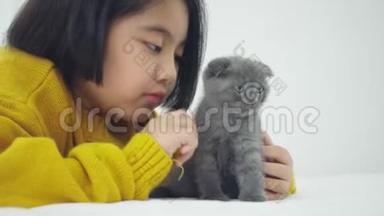 可爱的亚洲女孩和可爱的小猫玩耍，漂亮的女孩紧紧地抱着一只猫在室内