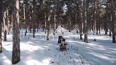 一位穿着白色羽绒服的年轻母亲穿过美丽如雪的冬松林，拉着雪橇