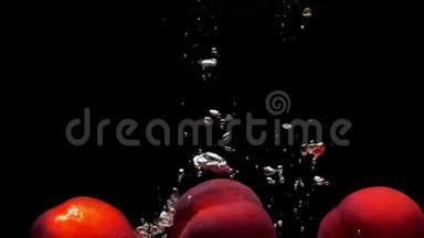 三个成熟的桃子在黑色的背景下<strong>落入</strong>透明的水中