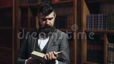 有胡子的人在书架背景上看书。 在图书馆看书的人。 大学生读书画像
