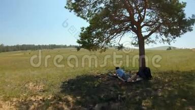 女孩躺在树下，在田野里画了一幅风景画