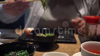 女人用木筷子吃海藻沙拉。 特写镜头。 中国筷子吃海藻沙拉