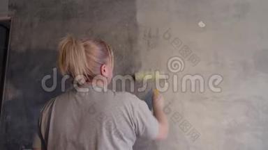 一个女人用滚筒在粉刷墙壁之前对墙壁进行处理。 用滚筒涂手。