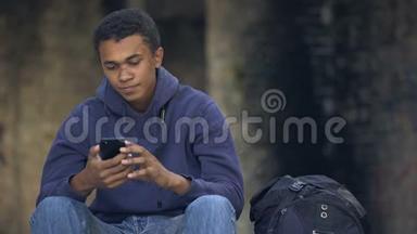 孤独的年轻人坐在街上听智能手机音乐，青春期的不安全感