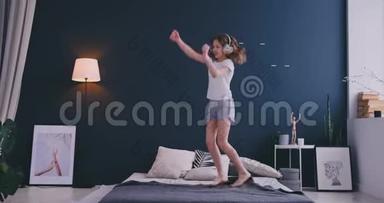 有趣可爱的小<strong>女孩</strong>戴着无线耳机跳舞，梳着梳子唱歌，在度假的<strong>早晨</strong>跳着床