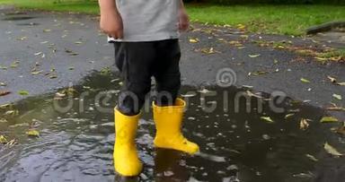 婴儿穿着黄色的橡胶靴子踩水坑