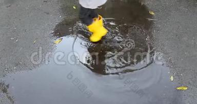 婴儿穿着黄色的橡胶靴子踩水坑