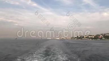 时光舟带着游客游过伊斯坦布尔海岸，带着美丽的房子，在水上留下一条小径